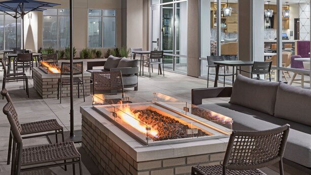 An outdoor patio area with a fire feature, seating, and a view of the interior. - Residence Inn by Marriott Chatsworth (Chatsworth)
