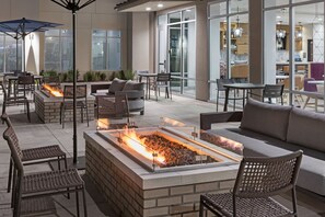An outdoor patio area with a fire feature, seating, and a view of the interior. - Residence Inn by Marriott Chatsworth (Chatsworth)