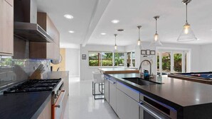 Una cocina moderna con una isla central, electrodomésticos de acero inoxidable e iluminación colgante.