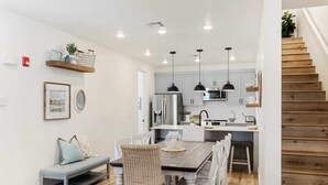 A modern kitchen with white cabinets, a wooden dining table, and pendant lights. - Anchor Oasis: Desert Color Lagoon + Beaches (St. George)