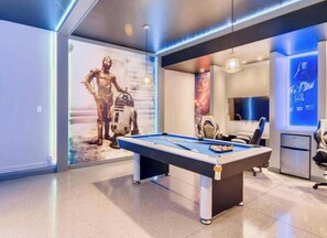 A modern room with a pool table, Star Wars-themed wall art, and a Star Wars poster.