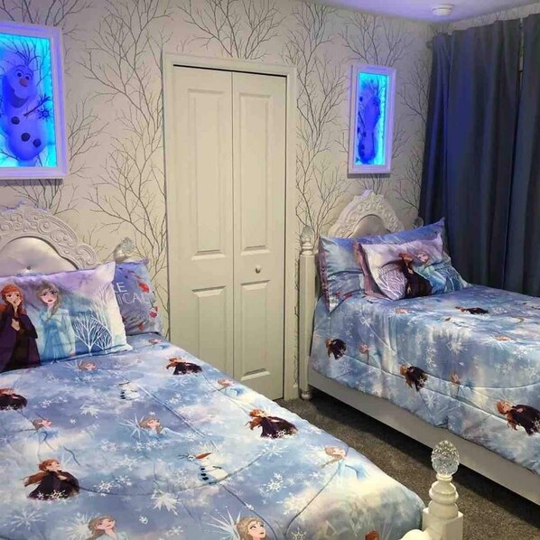 A bedroom with two beds, each with a 'Frozen' themed duvet cover, a white wardrobe, and a door with a frosted glass panel.