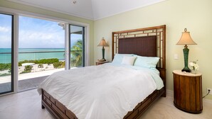 A bedroom with a large bed, two bedside tables, and a view of the ocean. - LUXURY BEACHFRONT Villa on EXQUISITE BEACH, crystal WATER. IN SANDCASTLE ESTATES (Sandy Point)