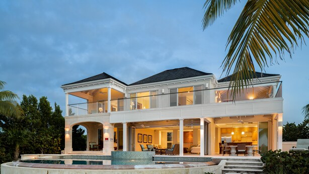 A two-story house with a balcony, a swimming pool, and a well-lit interior. - LUXURY BEACHFRONT Villa on EXQUISITE BEACH, crystal WATER. IN SANDCASTLE ESTATES (Sandy Point)