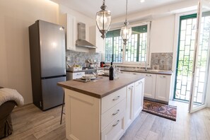 Una cucina moderna con mobili bianchi, un frigorifero in acciaio inossidabile e una grande isola con piano in marmo.