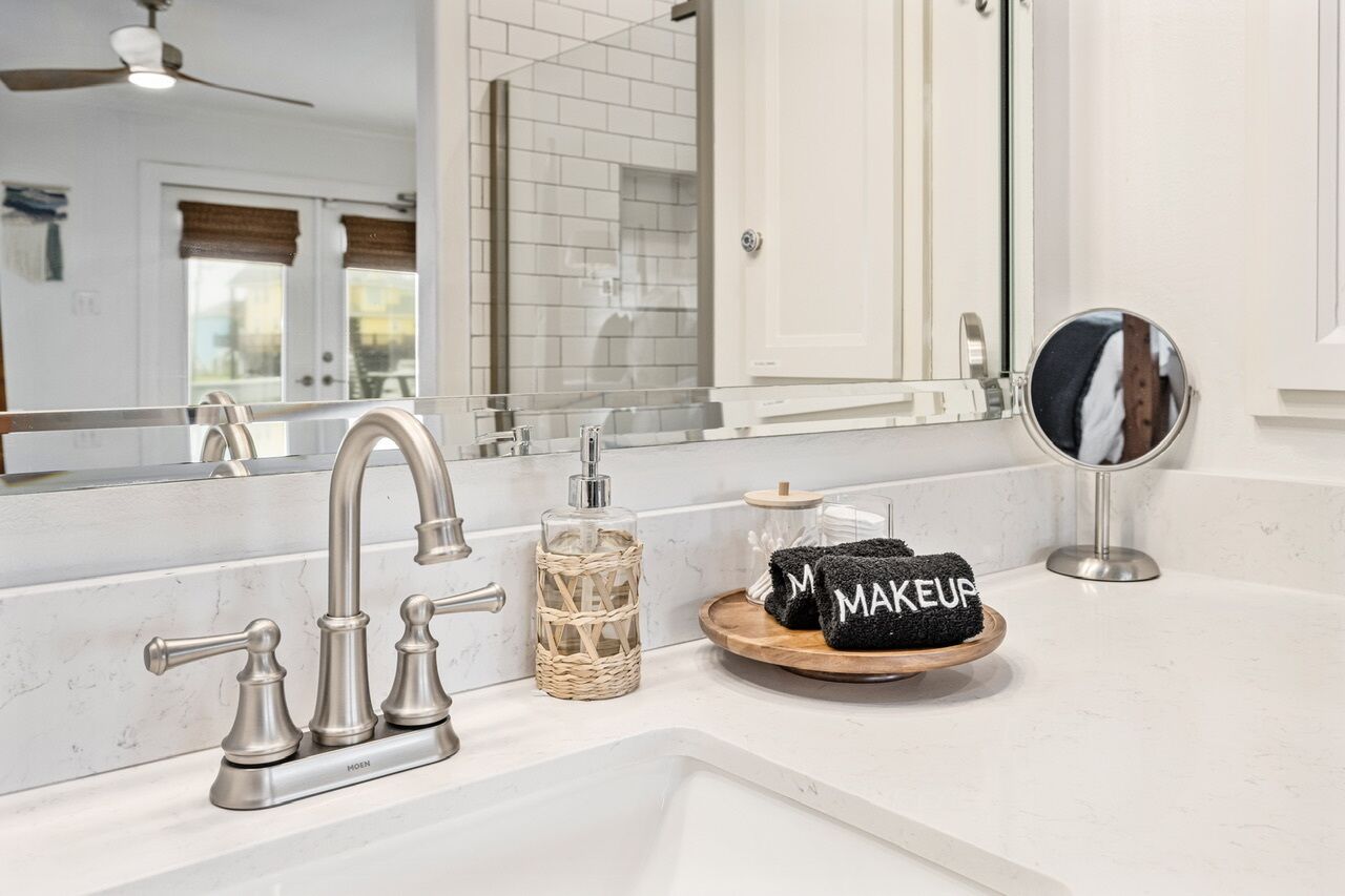 A bathroom with a white sink, a mirror, a towel rack, and a bottle of hand soap.