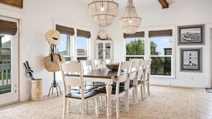 A dining area with a wooden table and chairs, a chandelier, and a view of the outdoors. - WATERCOLOR SKY BEACH HOUSE - Well-appointed house with great location!! (Crystal Beach)