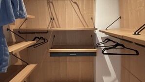 Un dressing avec des étagères en bois, une tringle et un meuble à tiroirs.