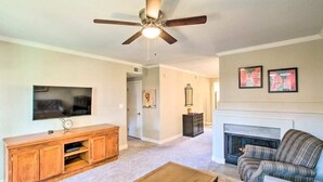 A living room with a ceiling fan, a flat-screen TV, a fireplace, and a sofa.