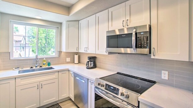 A modern kitchen with white cabinets, a stainless steel stove, and a microwave.