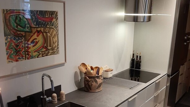 Una cucina moderna con un piano di lavoro nero, lavello in acciaio inossidabile e pavimento a scacchi.