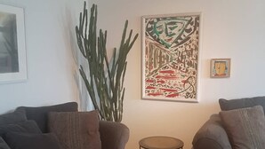 Un soggiorno con due divani grigi, un tavolino rotondo, un cactus e un quadro astratto appeso alla parete.