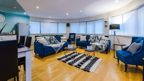 Un salon moderne avec un canapé bleu, un coin repas comprenant une table et des chaises, et une cuisine équipée d’un réfrigérateur.