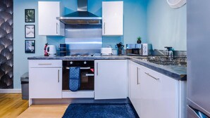 Une cuisine moderne avec des armoires blanches, une hotte de cuisinière en acier inoxydable, un four encastré et un évier.