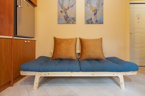 Une pièce avec un meuble en bois, un lit avec une literie bleue et deux oreillers marron, et deux tableaux accrochés au mur.