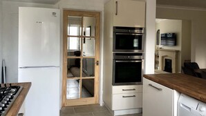 A compact kitchen with a white refrigerator, double ovens, and a microwave.