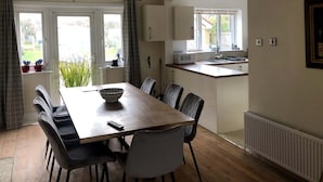 A dining area with a wooden table, black and white chairs, a bowl, and a remote control.