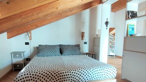 A bedroom with a bed, wooden beams, a nightstand, and a dresser. - Cozy stay in the heart of Mondovi (Mondovi')