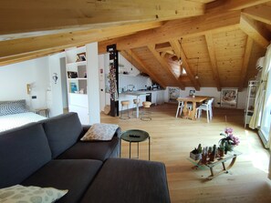 A cozy loft-style living space with a high ceiling, a dining area, and a kitchenette.