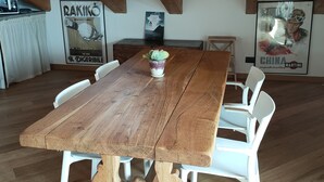 A wooden dining table with white chairs, a hanging light bulb, and posters on the walls. - Cozy stay in the heart of Mondovi (Mondovi')