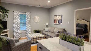 A modern living room with a grey sofa, a patterned armchair, a small table, and a decorative plant. - You'll be so happy, you'll want to "Just Dance" (Dandridge)