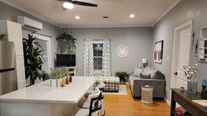 A modern kitchen with a central island, bar stools, a grey sofa, and a small table with decorative items. - You'll be so happy, you'll want to "Just Dance" (Dandridge)