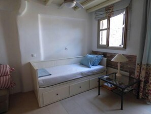 Ein kleines Zimmer mit einem Einzelbett, einem Fenster, einem Nachttisch und einem Stuhl.