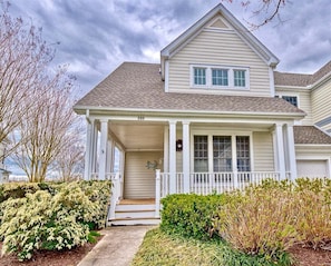 A two-story house with a porch, a front door, and a mailbox.