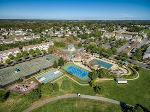 An aerial view of a residential area with multiple houses, a tennis court, and a swimming pool.