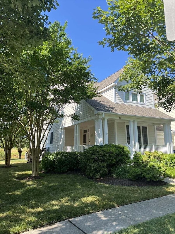 A two-story house with a porch, surrounded by trees and a well-maintained lawn.