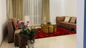Un salon avec un canapé marron, un tapis rouge et une table basse en verre.