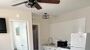 A modern kitchen with white cabinets, a white refrigerator, and a wooden floor. - One Bedroom Suite 107 (Wildwood)