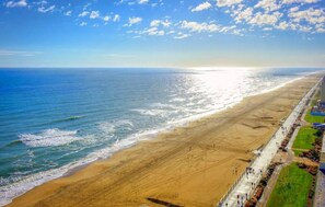 A beach with a long promenade, a clear sky, and the ocean.