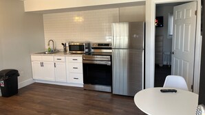 Une cuisine de taille réduite avec des meubles blancs, des appareils en acier inoxydable et un plancher en bois.