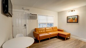 Una sala de estar con sofá, mesa, televisión y ventana con persianas.