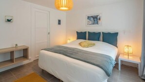A bedroom with a bed, bedside tables, a door, and a wall-mounted shelf. - Sologne house in the heart of nature, 15 minutes from Chambord Castle! (La Ferté-Saint-Cyr)