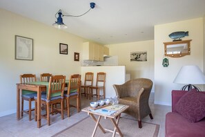 Cozy living space with a dining area and seating area, featuring a wooden table, wicker armchair, and red sofa.