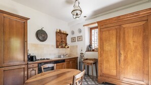 Una cocina con gabinetes de madera, una mesa de comedor y piso de baldosas.