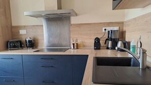 A modern kitchen with a stainless steel range hood, a built-in sink, and a coffee maker.