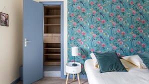 A bedroom with a bed, a bedside table with a lamp, a wardrobe, and a floral wallpaper.