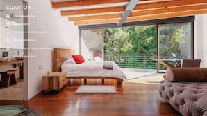 Een moderne slaapkamer met een extra groot tweepersoonsbed, een eigen badkamer, Perzische of open gordijnen, eenvoudige meubels, extra kussens en dekens, en een klein wastafel in de vorm van een boot.