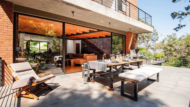 Een terras buiten met een eettafel voor zes personen, een bank en loungestoelen.