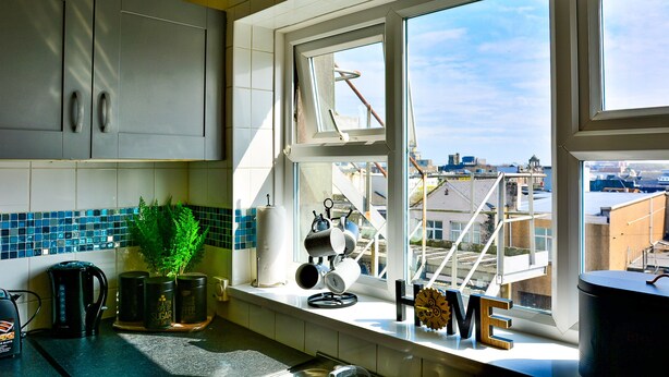 A kitchen with a window view, a coffee maker, a kettle, and a plant. - Captivating 3-bed House in Swansea Town Center (Swansea)