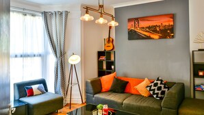 A modern living room with a sofa, a coffee table, and a bookshelf. - Captivating 3-bed House in Swansea Town Center (Swansea)