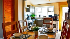 A dining area with a table set for four, chairs, and a view into the kitchen. - Captivating 3-bed House in Swansea Town Center (Swansea)