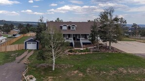 A two-story house with a front porch, a garage, and a fenced yard. - Walkout: Raspberry Mountain Family Farmhouse (Monument)