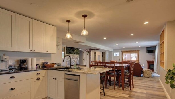 A modern kitchen with white cabinets, a central island, and pendant lighting. - Walkout: Raspberry Mountain Family Farmhouse (Monument)
