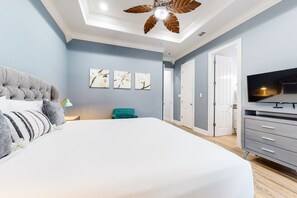 Une chambre avec un grand lit, un ventilateur de plafond, une télévision et une armoire.
