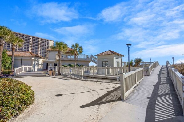 Une promenade en bord de mer avec un bâtiment, des palmiers et un ciel dégagé.