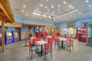 A restaurant with indoor seating, arcade games, and a thatched-roof area.